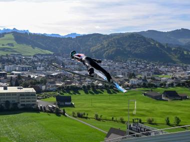 Skispringer mit Dorf im Hintergrund